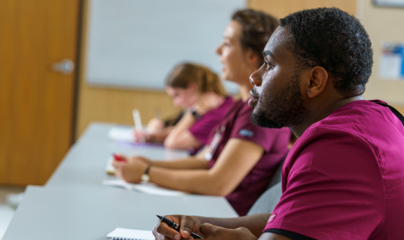 Picture of a student sitting at a table in a CNA class