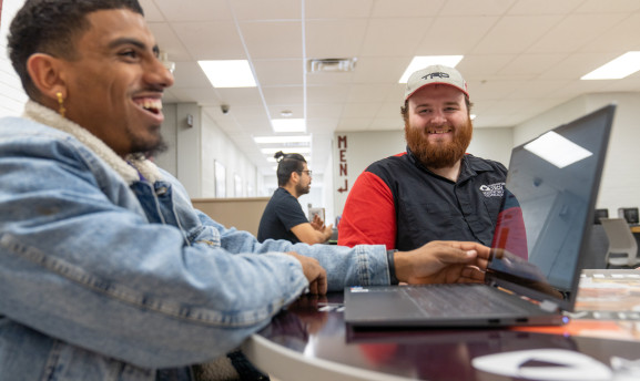 Students in the commons working on their laptop and chatting