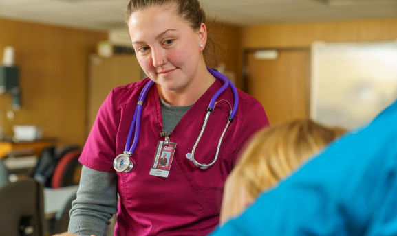 CNA student talking with patient in bed