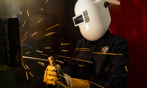 Image of a student welding on a piece of metal and sparks flying