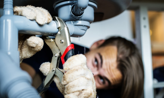 Man fixing kitchen sink with a wrench