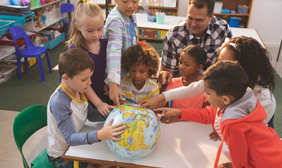 Childhood educator exploring the globe with a group of students